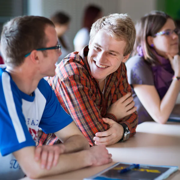 Jonge, knappe college student zitten in een klaslokaal vol met s — Stockfoto