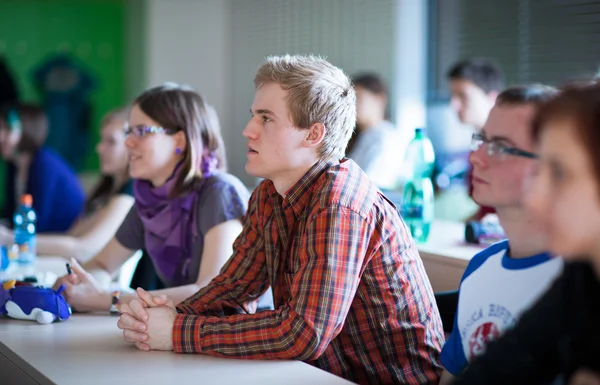 Jeune, beau étudiant assis dans une salle de classe pleine de s — Photo