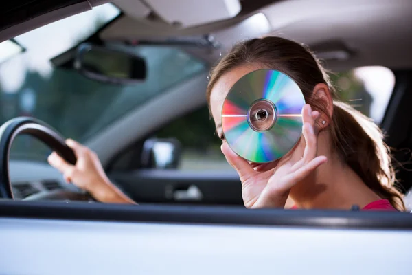 Joven conductora tocando música en el coche (cambiando CD ) —  Fotos de Stock