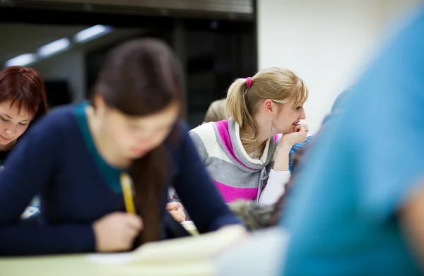 Pretty female college student sitting in a classroom Royalty Free Stock Images