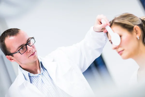 Concepto de optometría: joven guapo que examina sus ojos —  Fotos de Stock