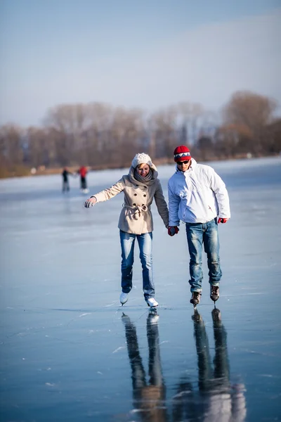 Paar schaatsen buitenshuis op een vijver op een mooie zonnige winterdag — Stockfoto