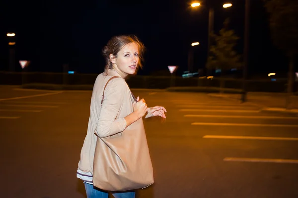 Scared young woman running from her pursuer in a deserted parkin — Stock Photo, Image