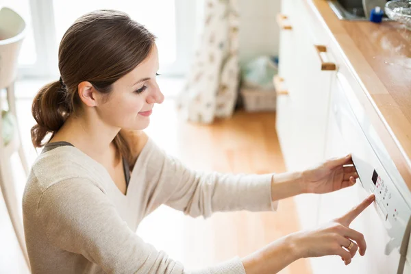 Hausarbeit: Junge Frau stellt Geschirr in die Spülmaschine — Stockfoto