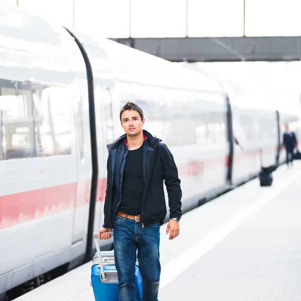 Acaba de llegar: joven guapo caminando por una plataforma en una moderna estación de tren —  Fotos de Stock