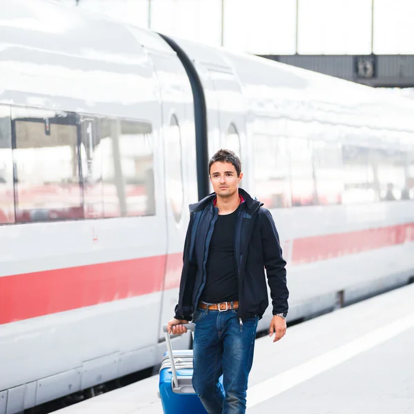 Acaba de llegar: joven guapo caminando por una plataforma en una moderna estación de tren — Foto de Stock