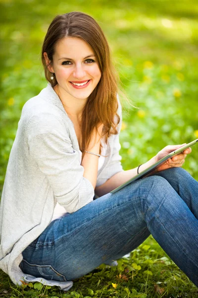 Jovem mulher usando seu computador tablet enquanto relaxa ao ar livre em — Fotografia de Stock