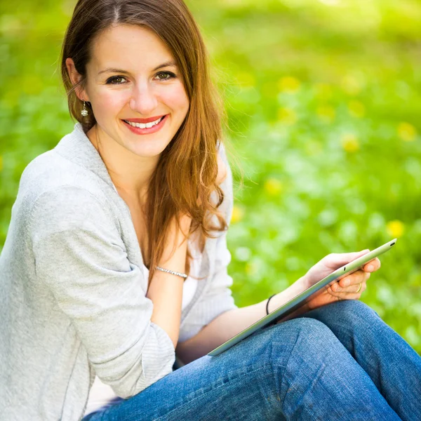 Jonge vrouw met behulp van haar tablet-pc terwijl u ontspant buitenshuis in — Stockfoto