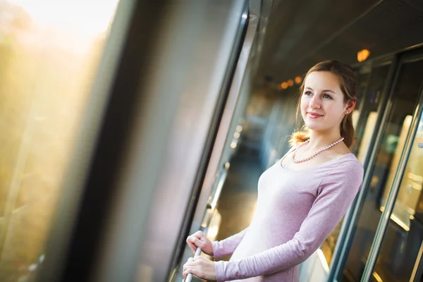 Giovane donna che viaggia in treno, guardando la campagna di passaggio mentre in piedi nel corridoio del treno — Foto Stock