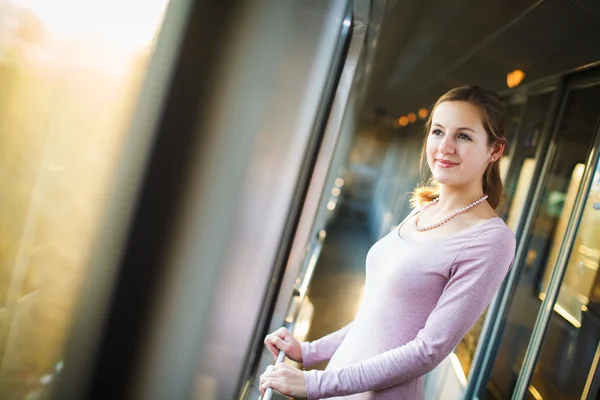 Jeune femme voyageant en train, regardant le côté campagne en passant tout en se tenant dans le couloir du train — Photo