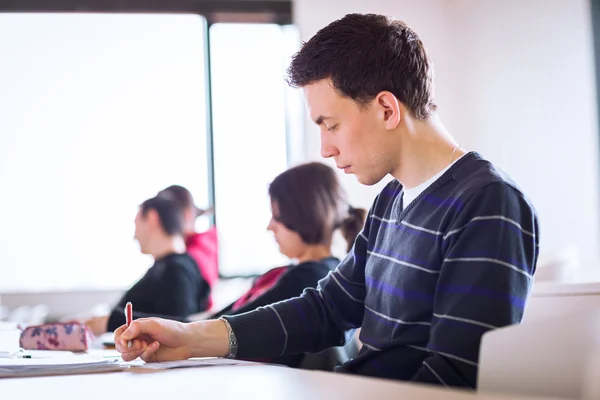 Junge, gut aussehende männliche College-Studentin sitzt in einem Klassenzimmer — Stockfoto
