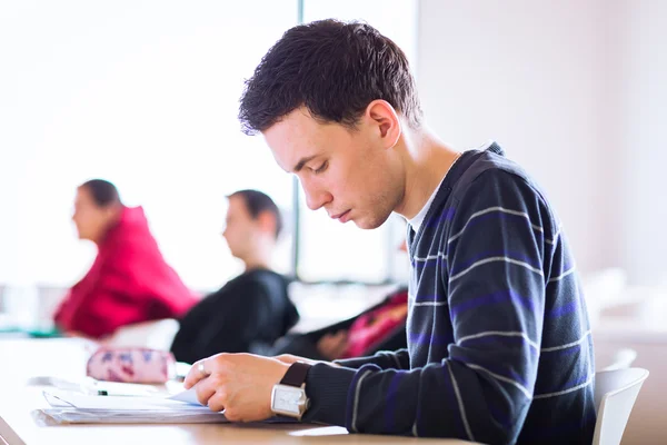 Jovem, bonito estudante universitário masculino sentado em uma sala de aula — Fotografia de Stock