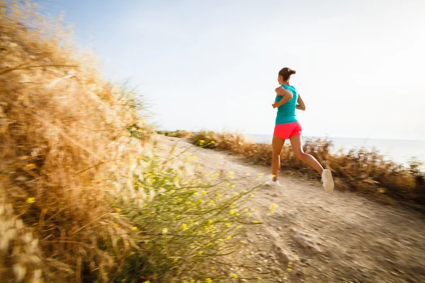 Junge Frau joggt abends an der Küste entlang — Stockfoto