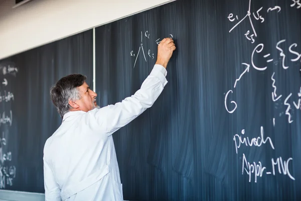 Profesor sénior de química escribiendo en la junta — Foto de Stock