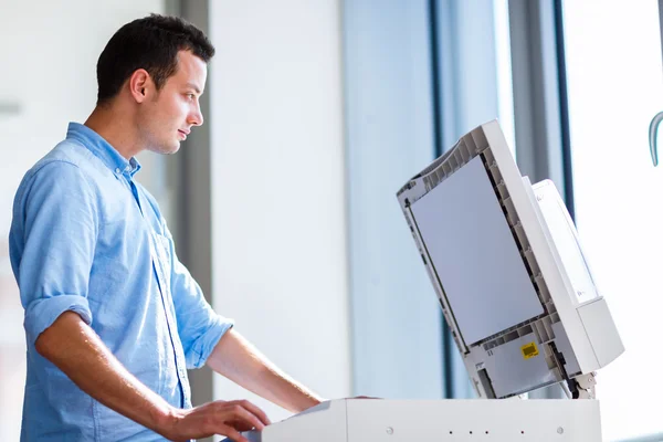 Beau jeune homme utilisant une machine à copier — Photo