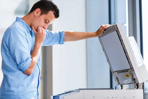 Handsome young man using a copy machine — Stock Photo, Image