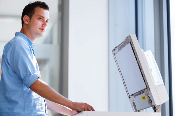 Handsome young man using a copy machine — Stock Photo, Image