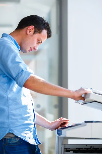 Handsome young man using a copy machine — Stock Photo, Image