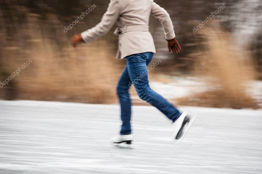 Young woman ice skating outdoors on a pond on a freezing winter