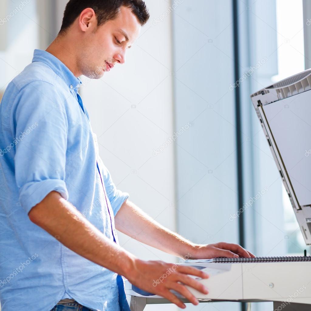 Handsome young man using a copy machine