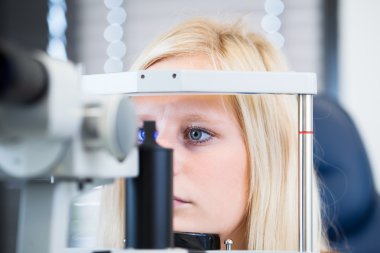 Optometri kavramı - güzel, genç bayan hasta muayene gözlerini yaptırıyor