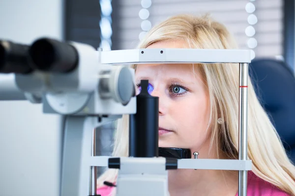 Optometry concept - pretty, young female patient having her eyes examined Stock Picture