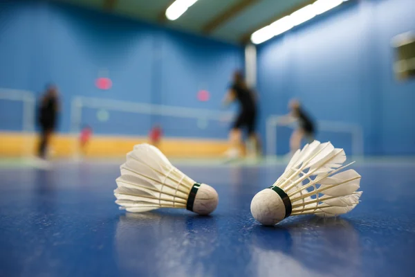 Bádminton - canchas de bádminton con jugadores compitiendo, lanzaderas en primer plano —  Fotos de Stock