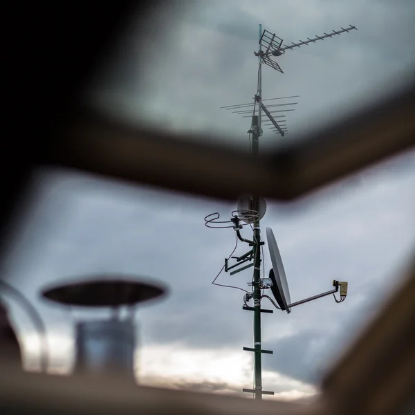 Antenler ve bir uydu çanağı bir çatı üzerinde — Stok fotoğraf