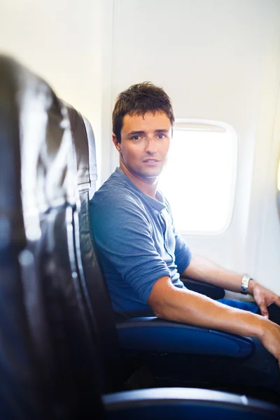 Beau jeune homme à bord d'un avion pendant le vol, looki — Photo