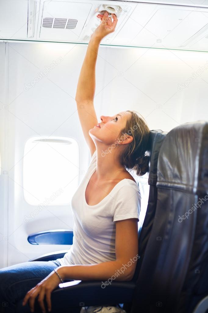 Female passenger adjusting air conditioning above her seat while