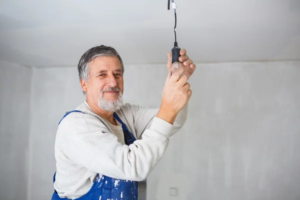 Homme âgé installant une ampoule dans un appartement récemment rénové i — Photo