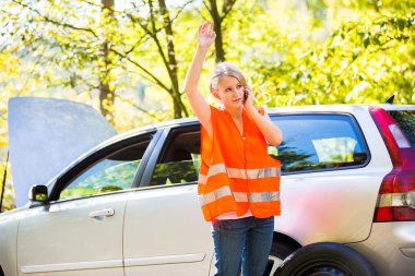 yüksek görünürlük yelek giyen genç kadın sürücü arama