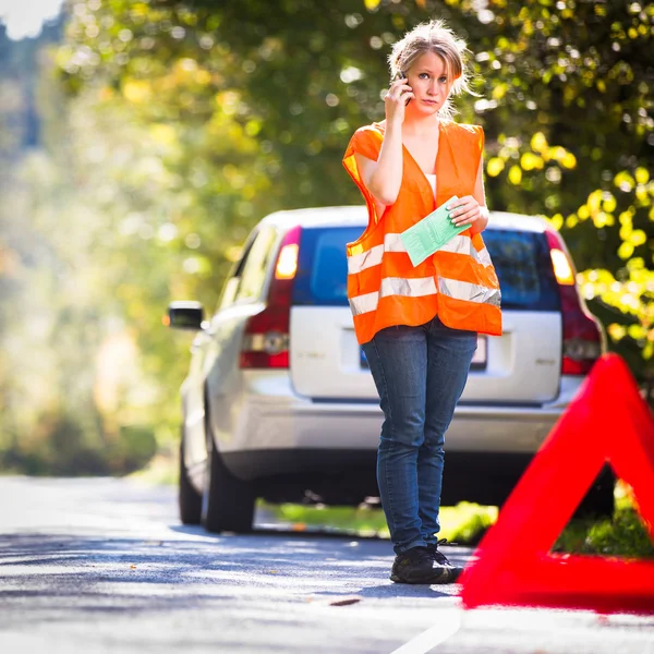 Young female driver wearing a high visibility vest, calling — Stock Photo, Image