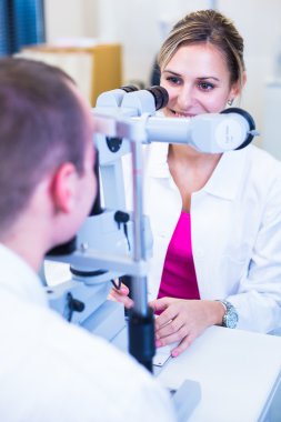 Optometri kavramı - yakışıklı genç adam gözlerini muayene yaptırıyor