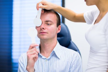Optometri kavramı - gözlerini muayene olan yakışıklı genç