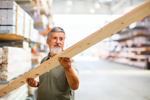 Hombre mayor comprando madera de construcción en una tienda de bricolaje — Foto de Stock