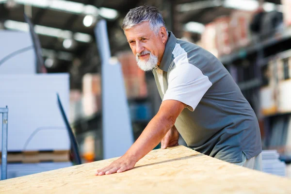 Starszy człowiek kupując drewno budowlane w sklepie z materiałami budowlanymi — Zdjęcie stockowe
