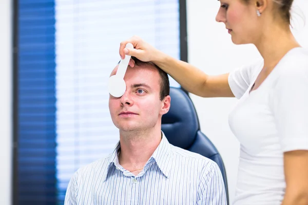 Optometrie koncept - pohledný mladý muž s jeho oči zkoumal — Stock fotografie