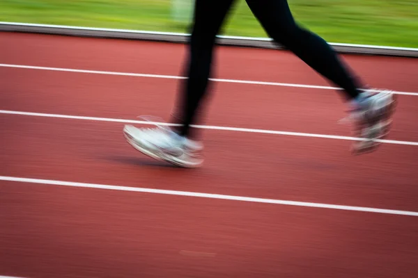 Giovane donna che corre in uno stadio di atletica leggera (movimento sfocato — Foto Stock