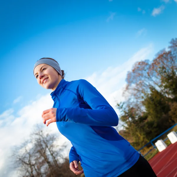 Jonge vrouw draait op een track & field stadion — Stockfoto