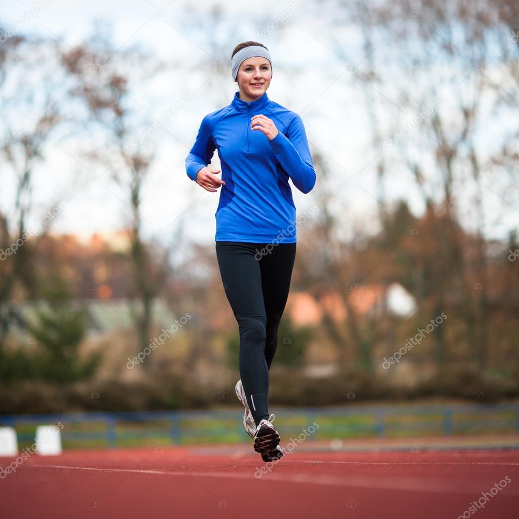 Young woman running at a track and field stadium