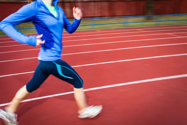 Молода жінка біжить на трасі та польовому стадіоні — стокове фото