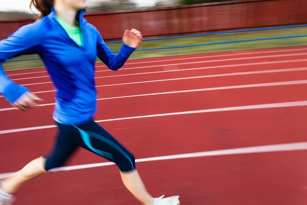 Mujer joven corriendo en un estadio de atletismo — Foto de Stock