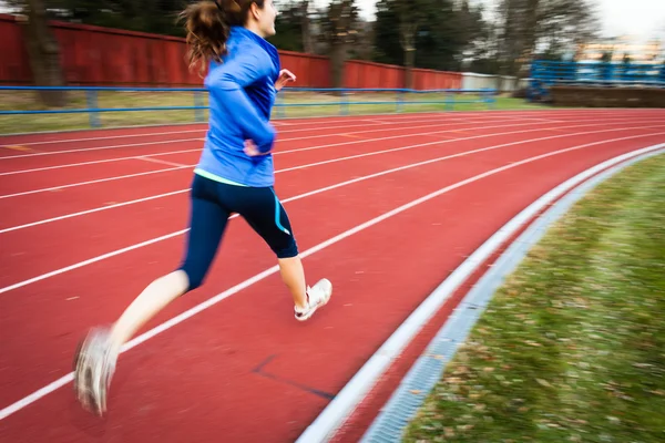 Young woman running at a track and field stadium — Stock Photo, Image