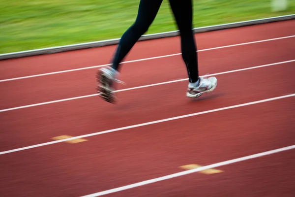 Jonge vrouw draait op een track & field stadion — Stockfoto