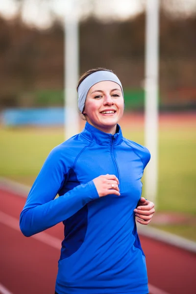 Young woman running at a track and field stadium Stock Photo