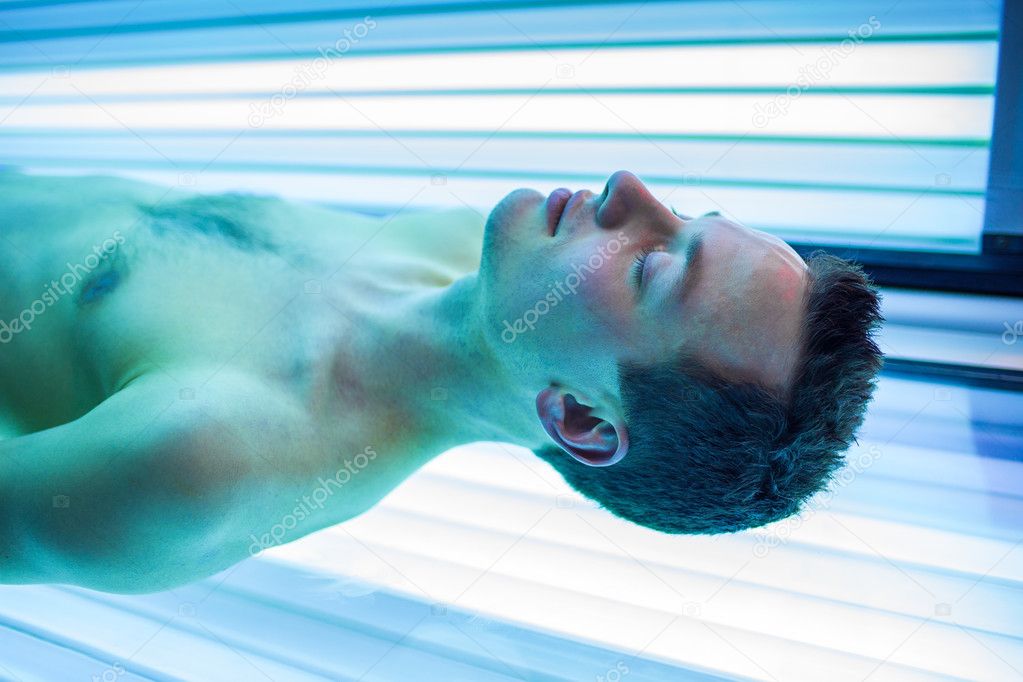 Handsome young man relaxing during a tanning session in a modern