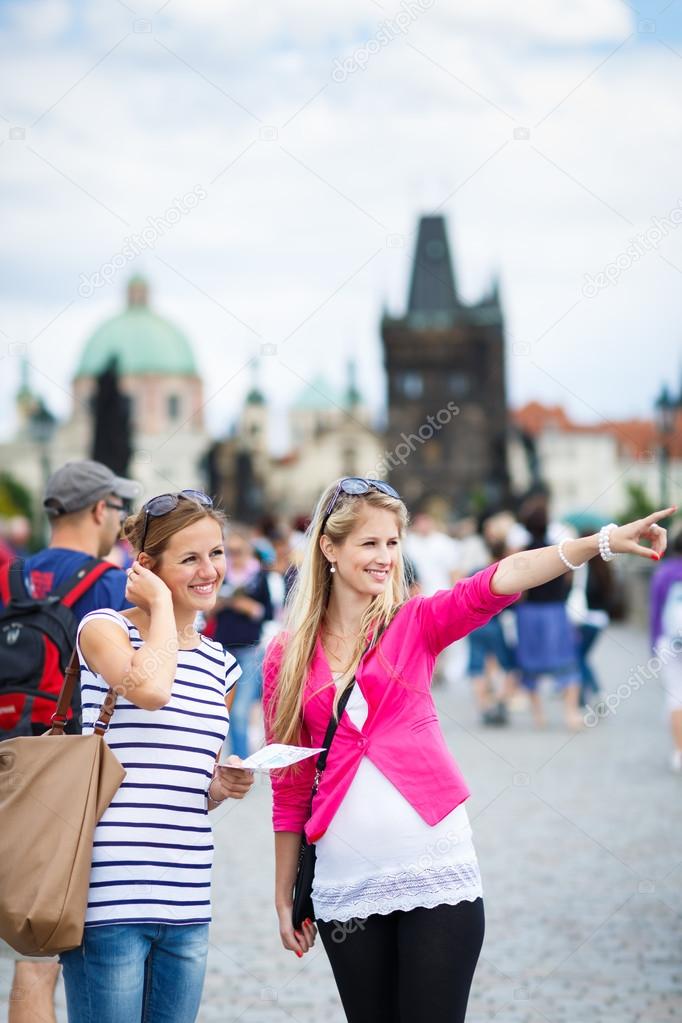 Two female tourists walking along the Charles Bridge while sight