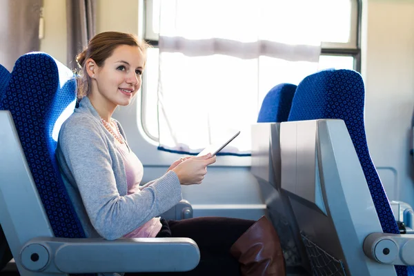 Mujer joven usando su tableta mientras viaja en tren — Foto de Stock