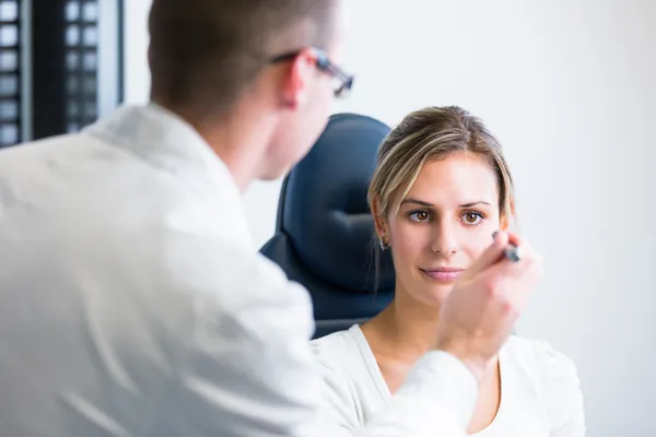 Concepto de optometría: mujer joven y bonita que examina sus ojos —  Fotos de Stock